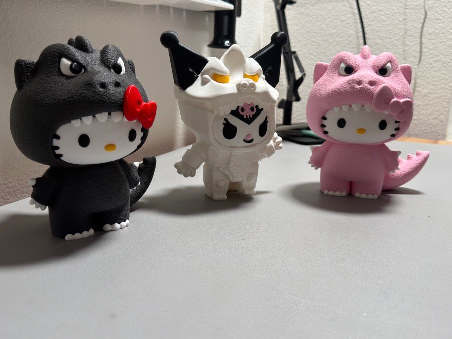 Three kitty figures in monster costumes