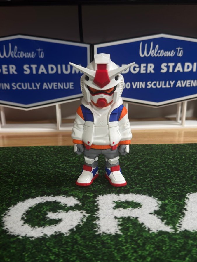 Mecha figure standing on turf between two stadium signs